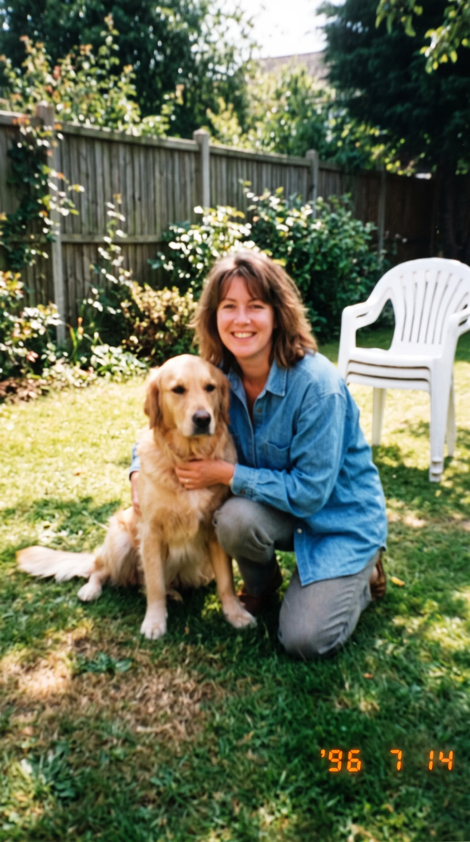 Blurry, out-of-focus 1990s snapshot of a woman kneeling in a garden with her golden retriever